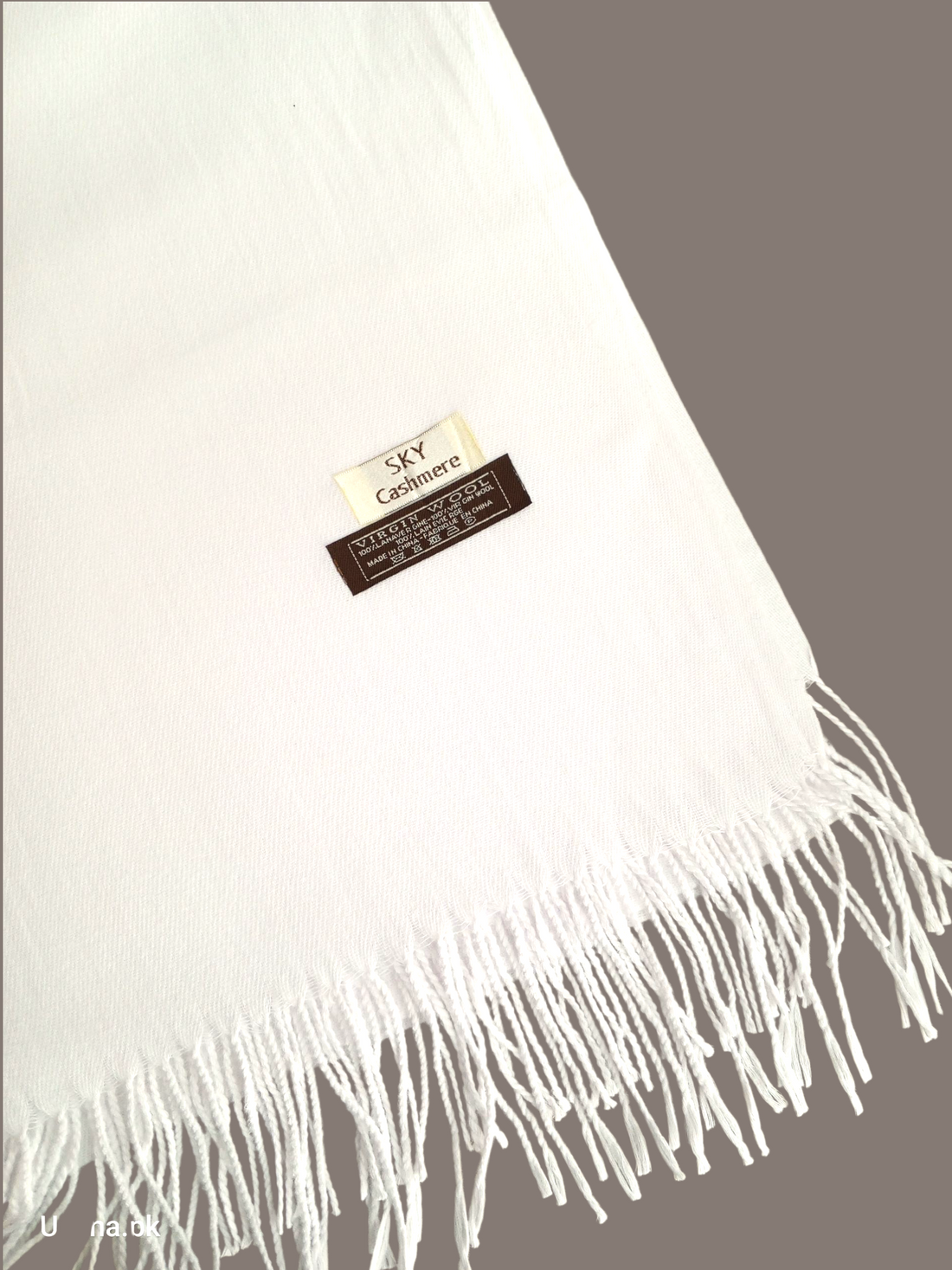 White Woolen Shawl with fringes on a gray background.