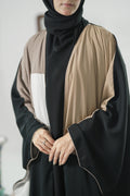 Model wearing a black and beige kaftan  abaya with a plain background